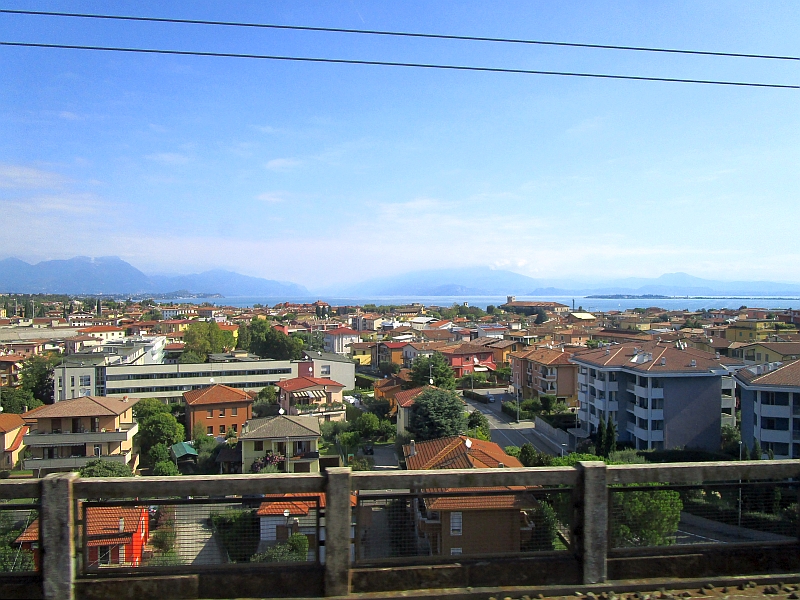 Blick vom Zug über die Dächer von Desenzano del Garda zum Gardasee