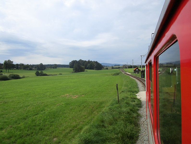 Blick durchs Zugfenster auf die Strecke der Attergaubahn