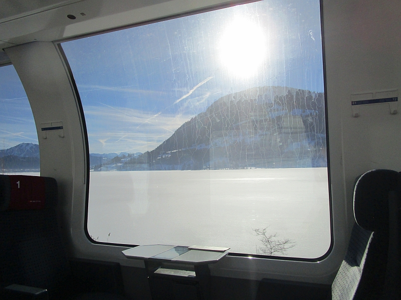 Blick aus dem Zugfenster auf den zugefrorenen Großen Alpsee