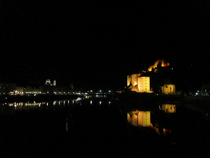 Einfahrt nach Passau, rechts Veste Niederhaus am Zusammenfluss von Ilz und Donau, darüber die Veste Oberhaus. Links die Altstadt mit den illuminierten Türmen des Doms.